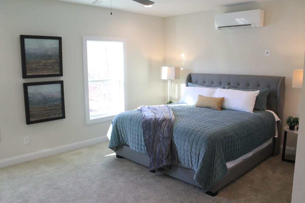 Bedroom with a queen bed and a window with a mini-split air conditioner on the wall.