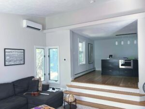 A wide view of a living room inside a home with a mini-split air conditioner mounted on the upper wall.